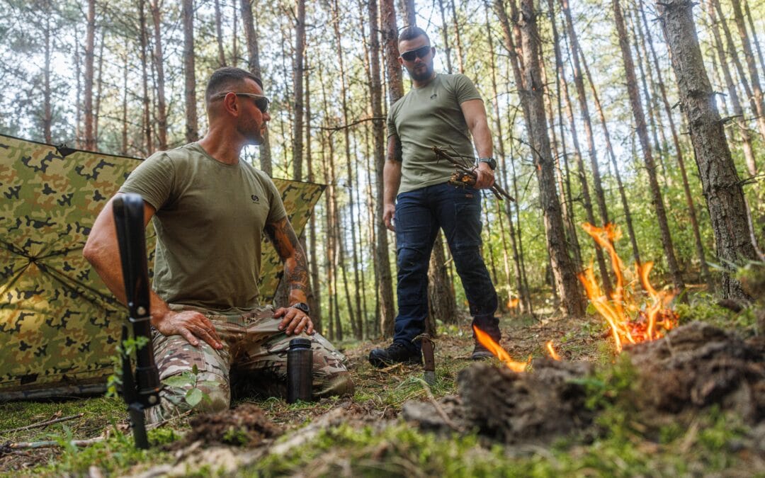 Dwóch mężczyzn w odzieży Durabo podczas biwaku w lesie - odzież taktyczna i outdoorowa na wyprawę.